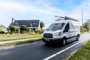 installatiebus zonnepanelen SolarNRG met huis met zonnepanelen op de achtergrond