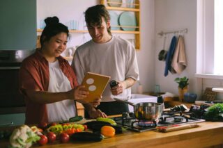 Man en vrouw koken met tablet